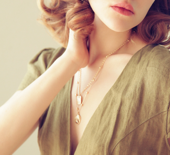 Image of short haired woman wearing gold necklace.